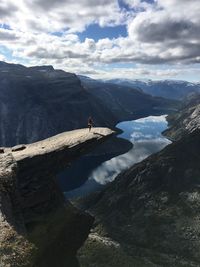 Mid distance view of woman exercising on mountain against cloudy sky