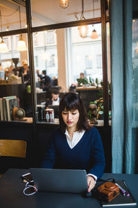 Confident businesswoman using laptop at desk in creative office