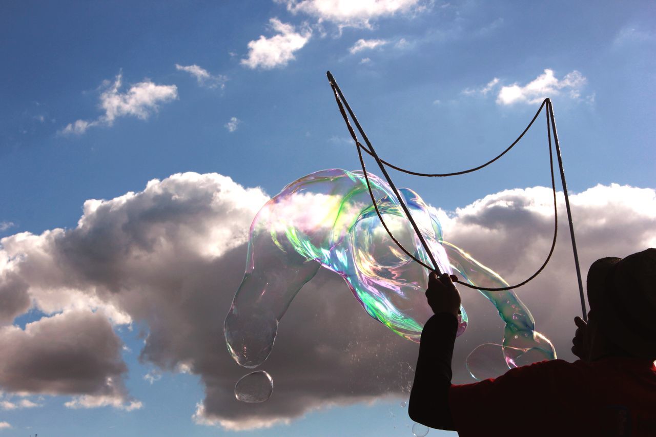 sky, leisure activity, cloud - sky, low angle view, blue, lifestyles, holding, unrecognizable person, cloud, men, enjoyment, outdoors, motion, nature, fun, day, arts culture and entertainment, person