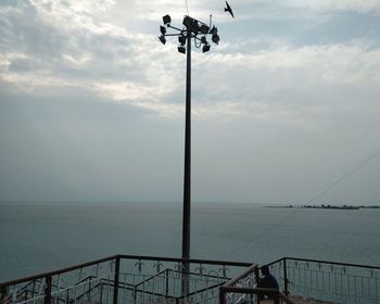 Low angle view of street light by sea against sky