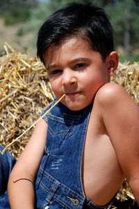 Portrait of boy with straw in mouth sitting outdoors