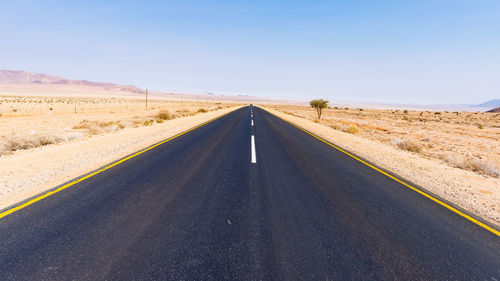 Road amidst desert against clear sky