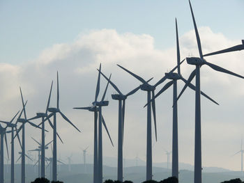 Low angle view of windmills against sky