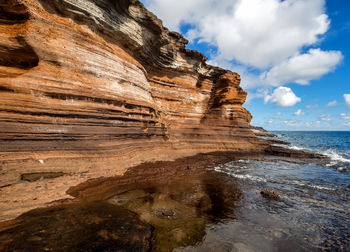 Rock formation in sea against sky