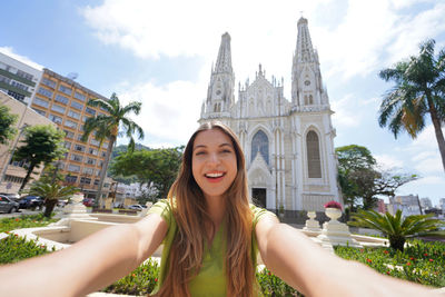 Young tourist woman taking self portrait with vitoria cathedral, espirito santo, brazil.