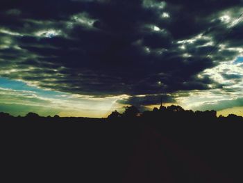 Silhouette of trees against cloudy sky