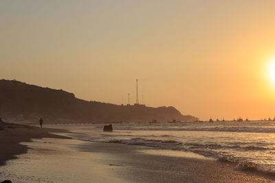 Scenic view of beach against clear sky during sunset