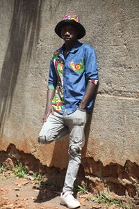 Portrait of young man standing against wall