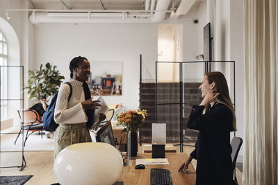 Happy female business professionals greeting each other at coworking office