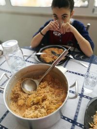 Portrait of girl drinking water while sitting at table