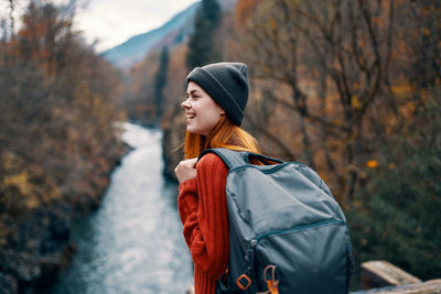 Young woman looking away while standing against trees during winter