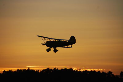 Silhouette of seaplane over lush forest