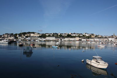 Boats moored at harbor against clear blue sky