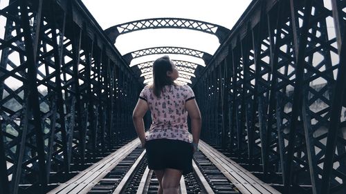 Rear view of woman standing on railroad bridge