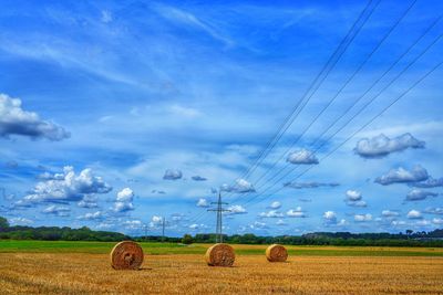 Hay bales on field against sky