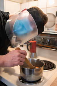 Man wearing face shield preparing food at kitchen