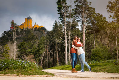 Women embracing against trees and plants