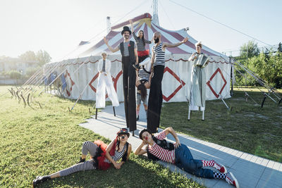 Male and female performers outside circus tent during sunny day