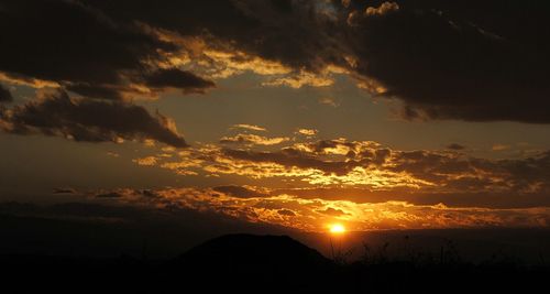 Scenic view of dramatic sky over silhouette landscape