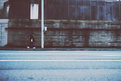 Man walking on side by road against building