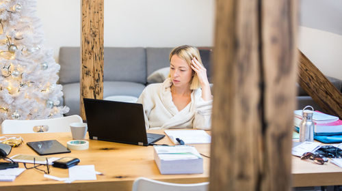 Businesswoman working at home by christmas tree