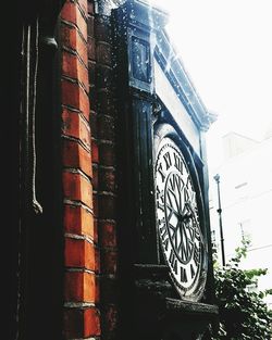 Low angle view of clock on building against sky