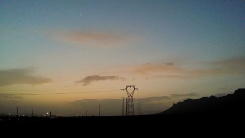 Low angle view of silhouette electricity pylon against sky during sunset