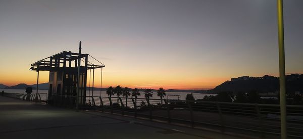 Silhouette pier over sea against sky during sunset