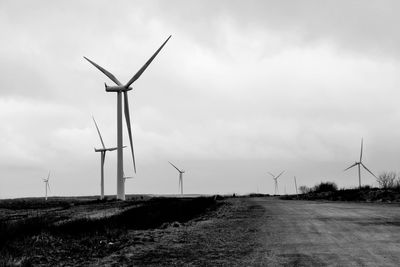 Windmills on field against sky