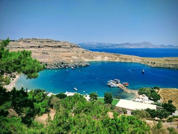 High angle view of boats on sea shore against clear blue sky