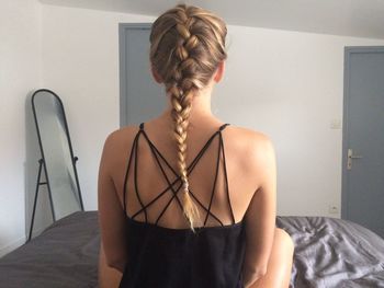 Rear view of woman with braided hair on bed at home