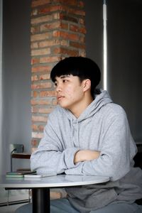 Young man sitting on table against wall