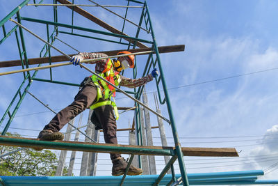 Low angle view of man working against sky