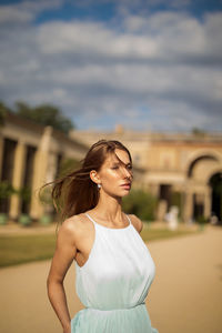 Young woman looking away while standing outdoors