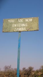 Low angle view of road sign against clear blue sky