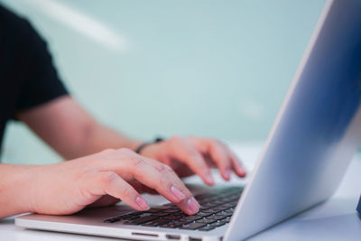 Cropped hand of person using laptop on table