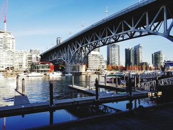 Bridge over river in city against sky