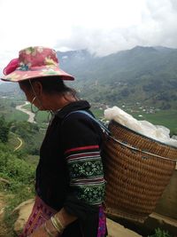 Rear view of woman standing on mountain against sky