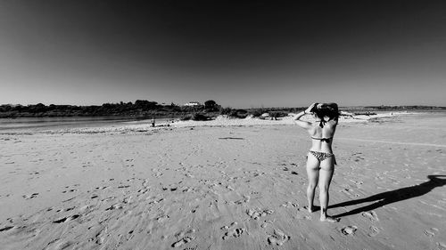 Woman standing on beach against clear sky