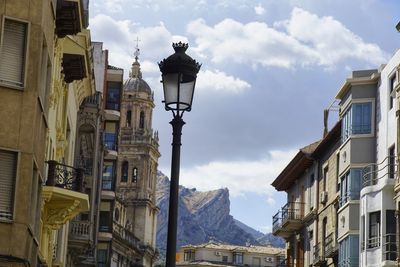 Low angle view of street light amidst buildings against sky