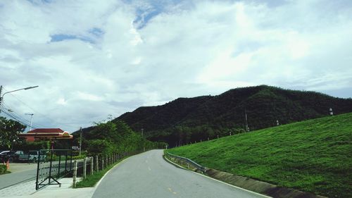 Empty road by trees against sky