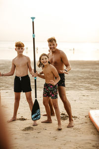 Happy family with oars during paddleboard training at beach on vacation