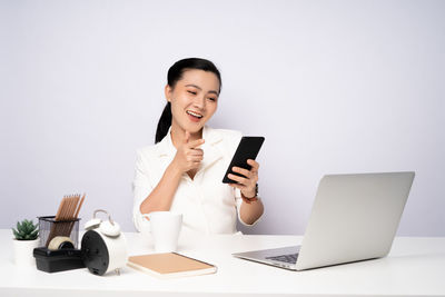 Young woman using laptop on table against white background