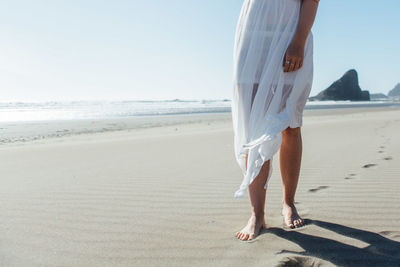 Low section of young woman standing on beach