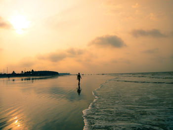 Silhouette people on beach against sky during sunset