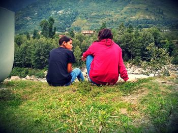 Rear view of couple sitting in forest