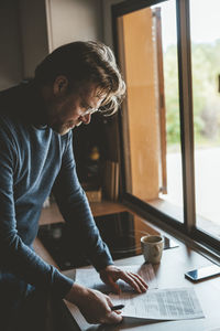 Man examining document in kitchen at home