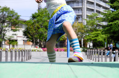 Low section of girl on sidewalk in city