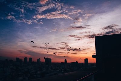 Silhouette buildings in city against sky during sunset