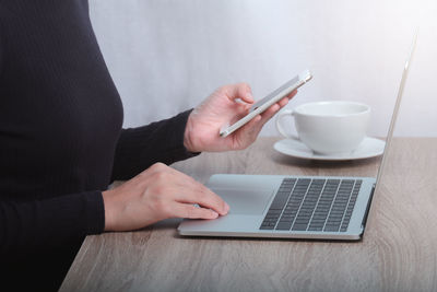 Midsection of man using smart phone on table